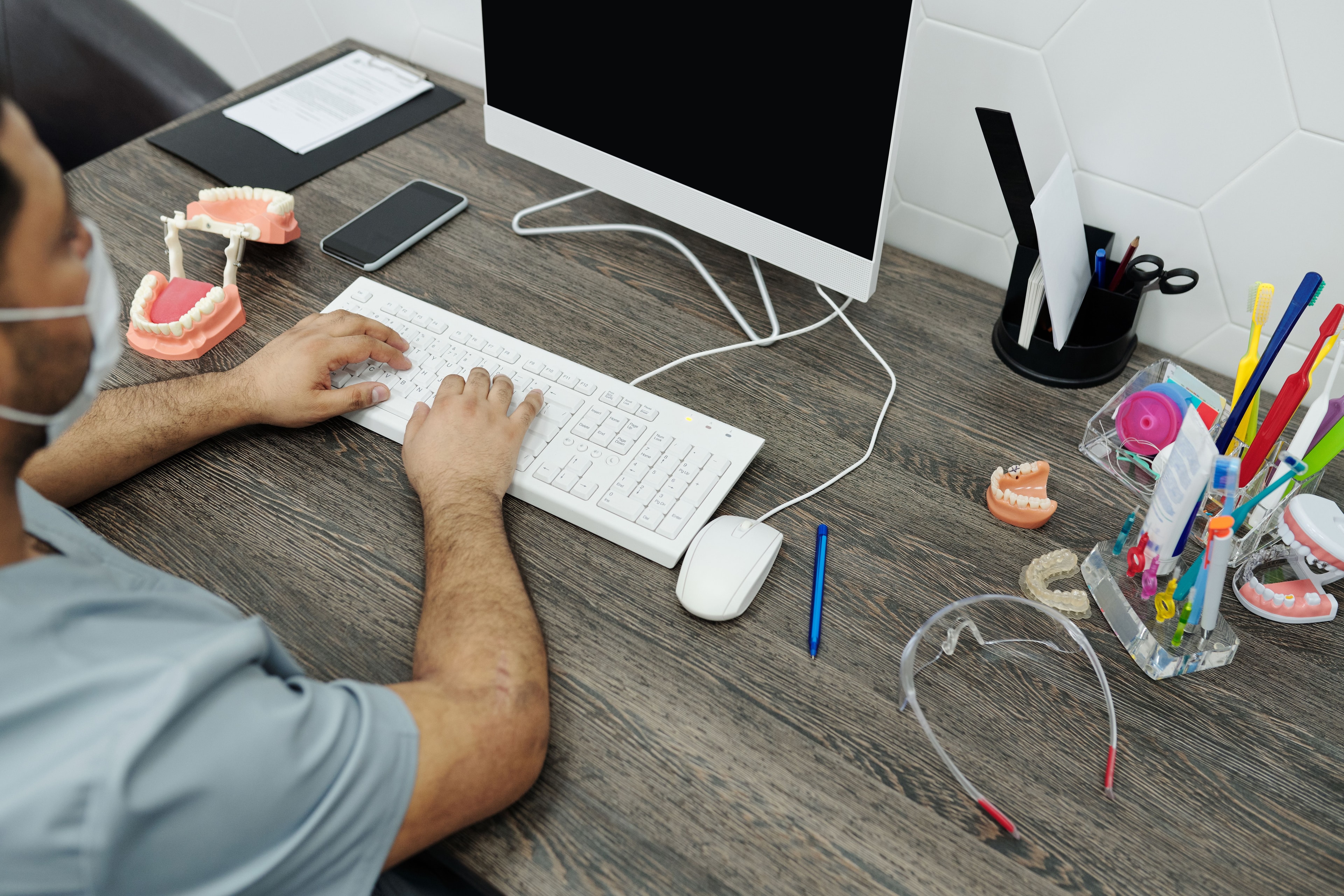 Tandlæge arbejder digitalt ved et skrivebord med tandmodeller.