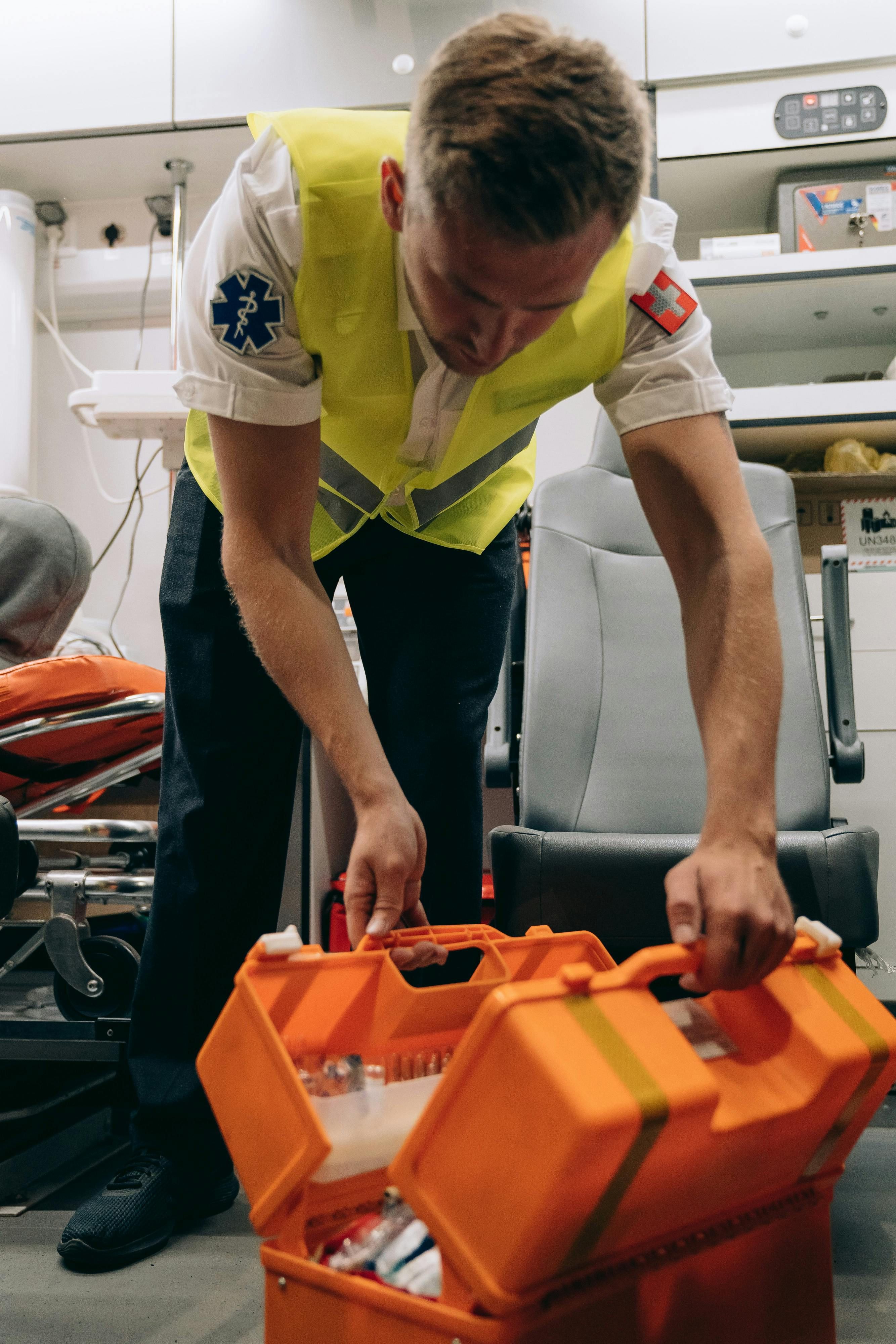 Ambulancemedarbejder åbner en orange udstyrskasse i en ambulance.