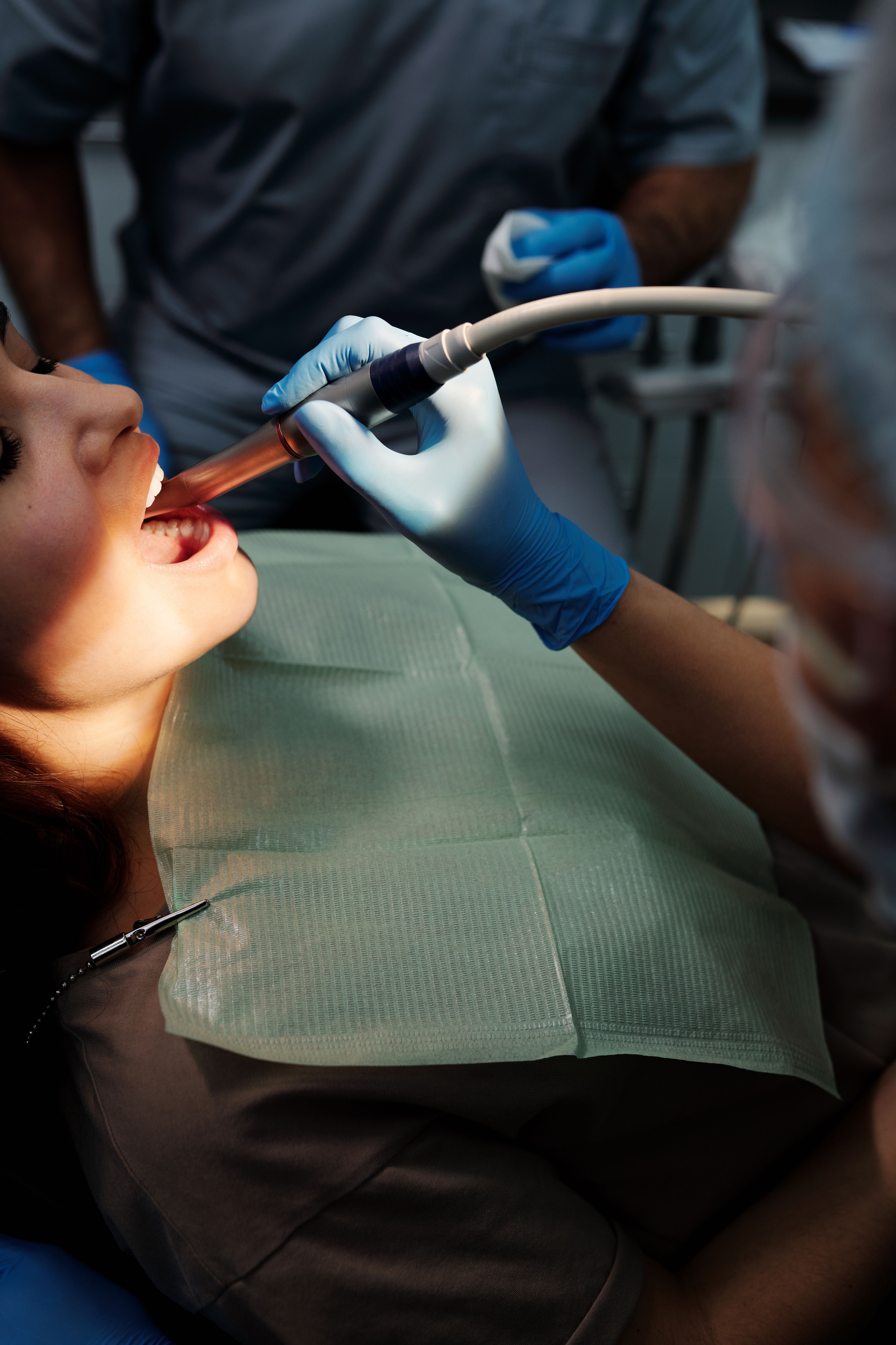 Behandler arbejder i en patients mund med sug og instrument.