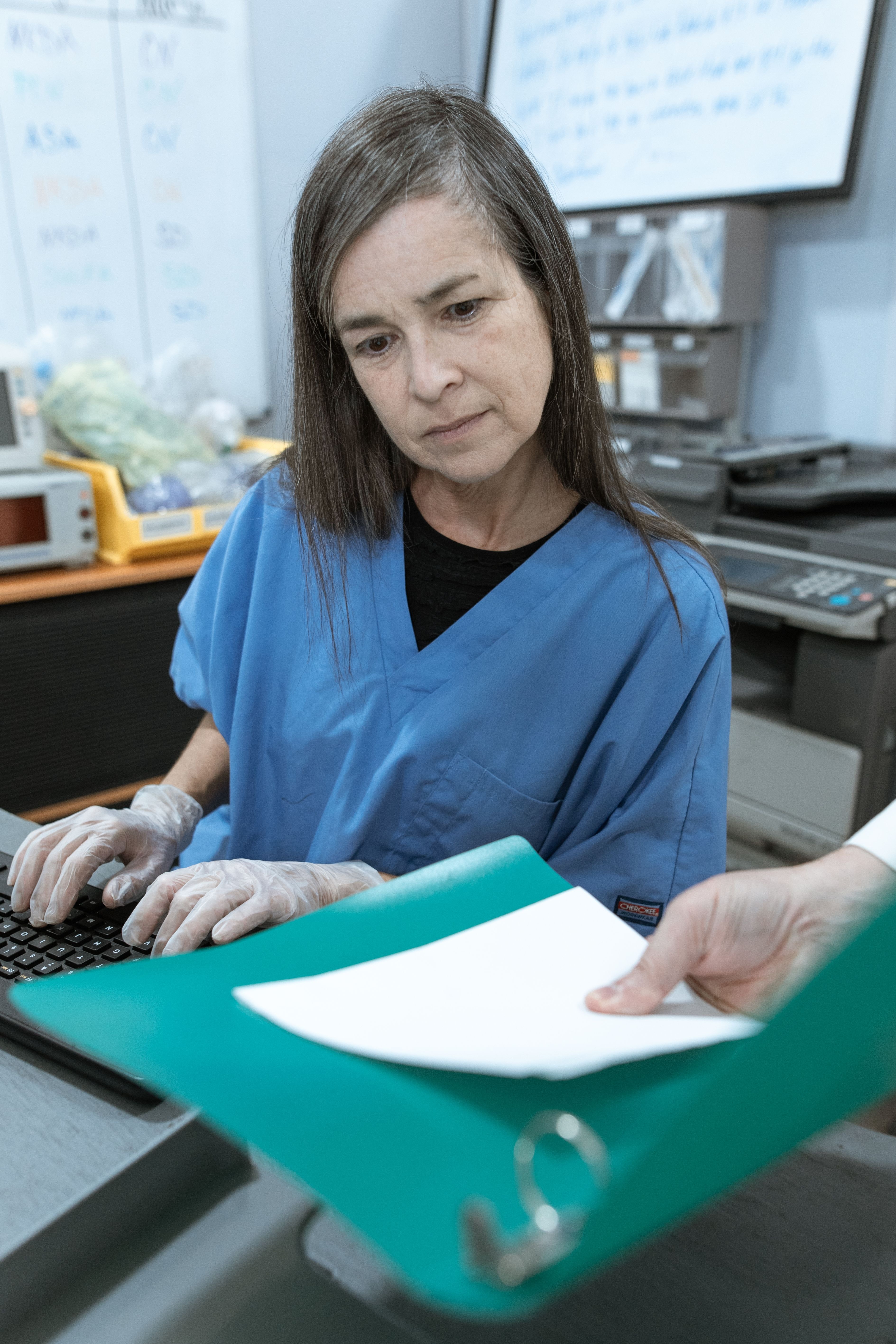 Klinikmedarbejder gennemgår et dokument ved en computer.