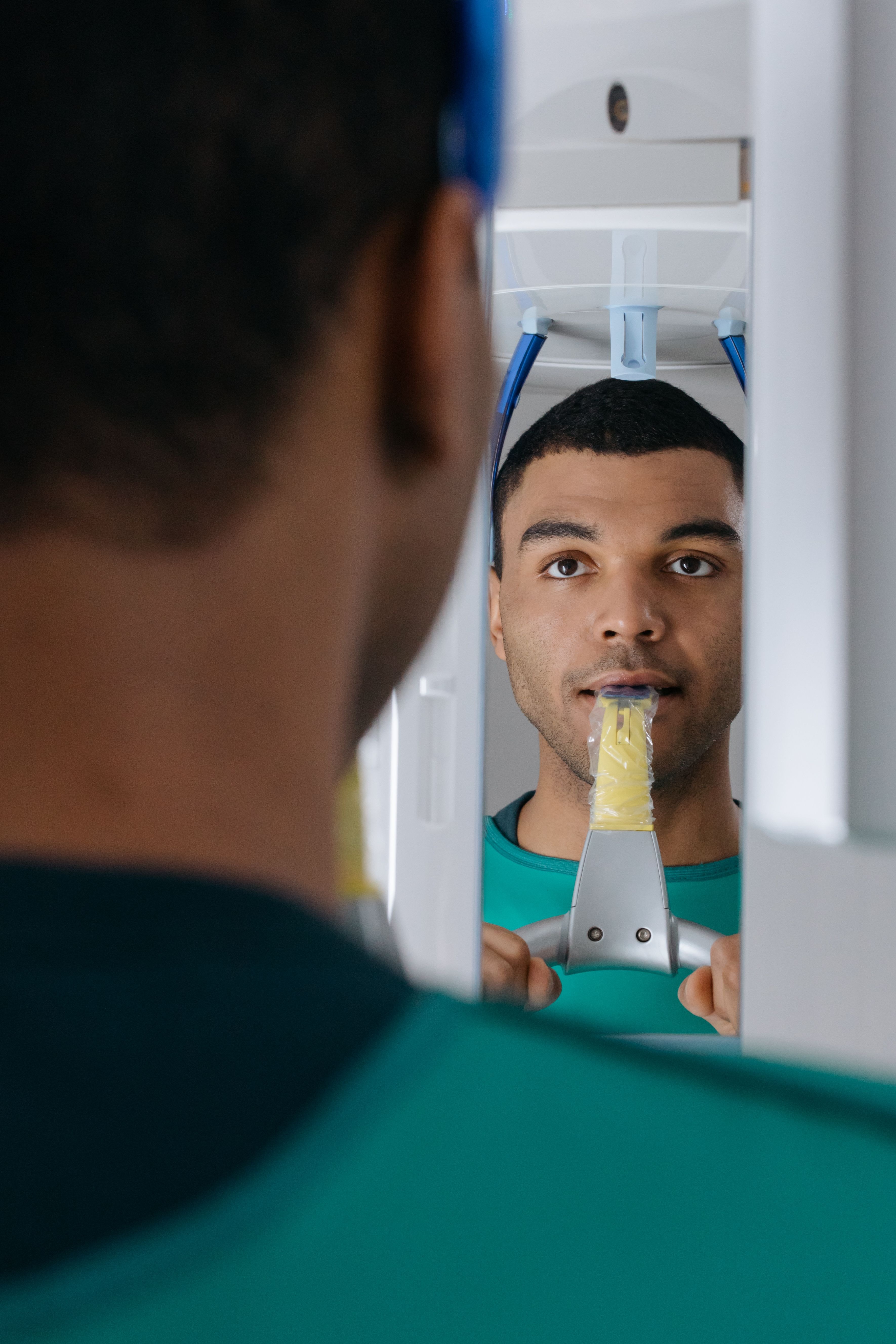 Patient står ved dentalbilledudstyr med en bidepind.