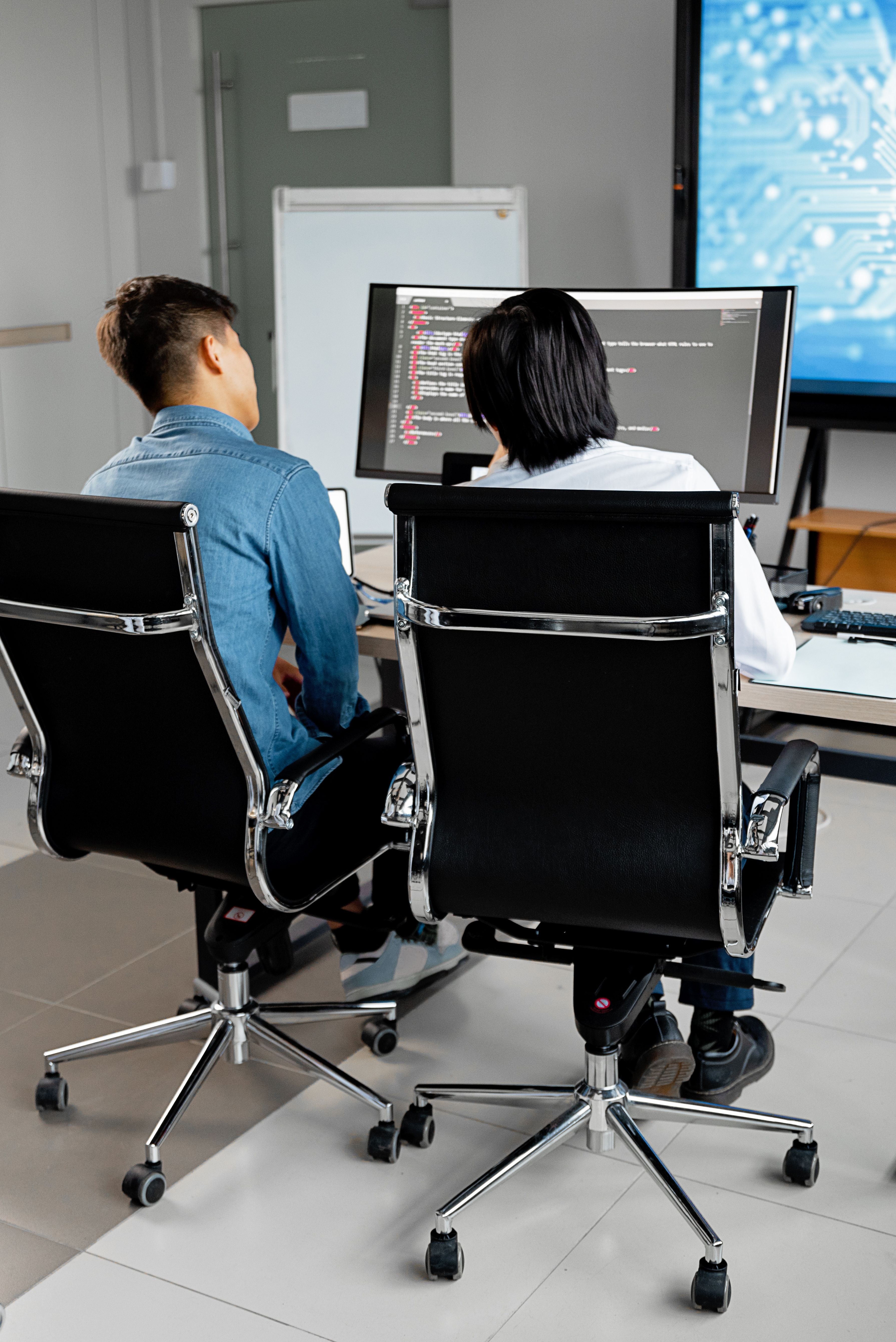 To personer arbejder sammen ved computerskærme med kode.