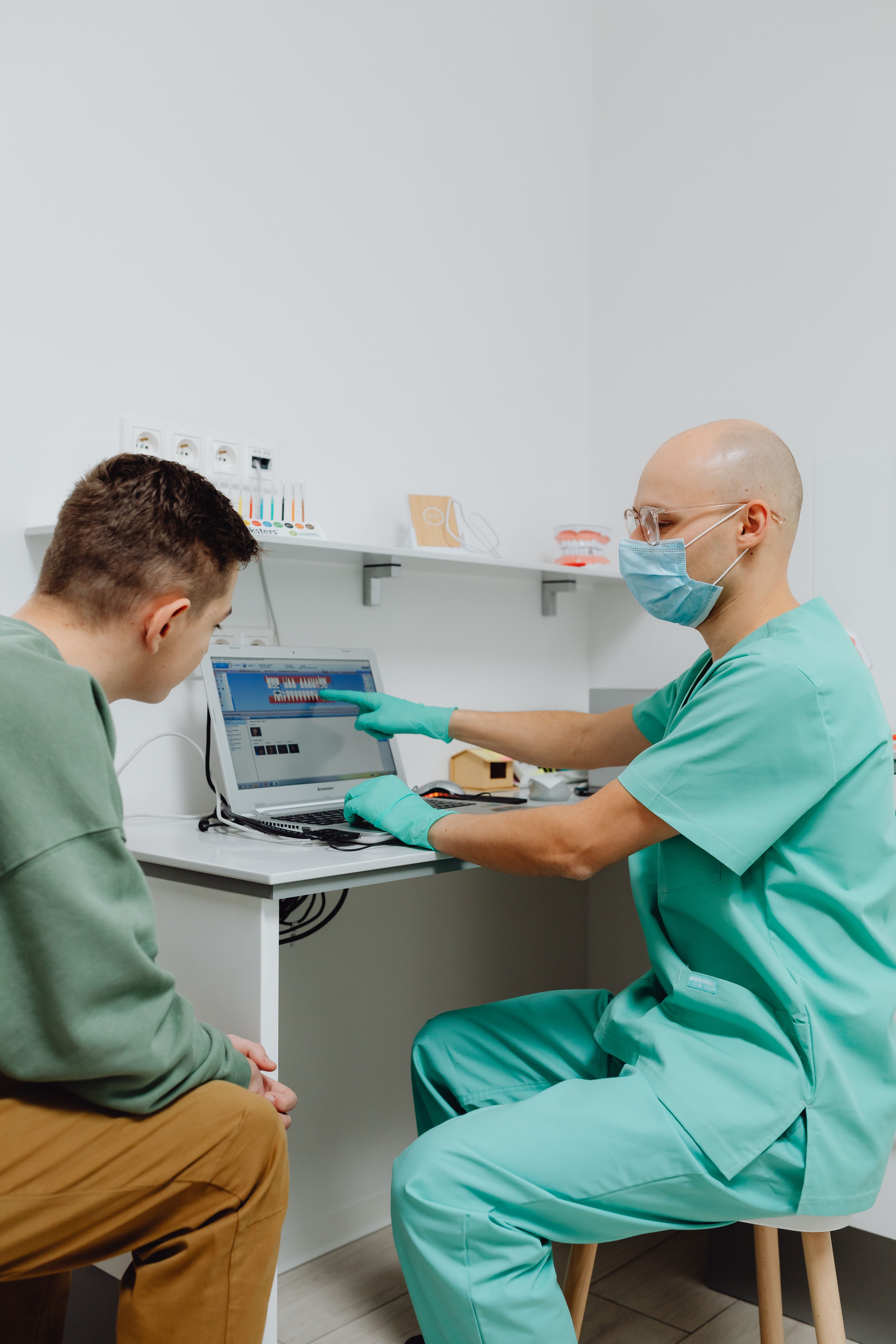 Tandlæge gennemgår oplysninger på en skærm sammen med en patient.