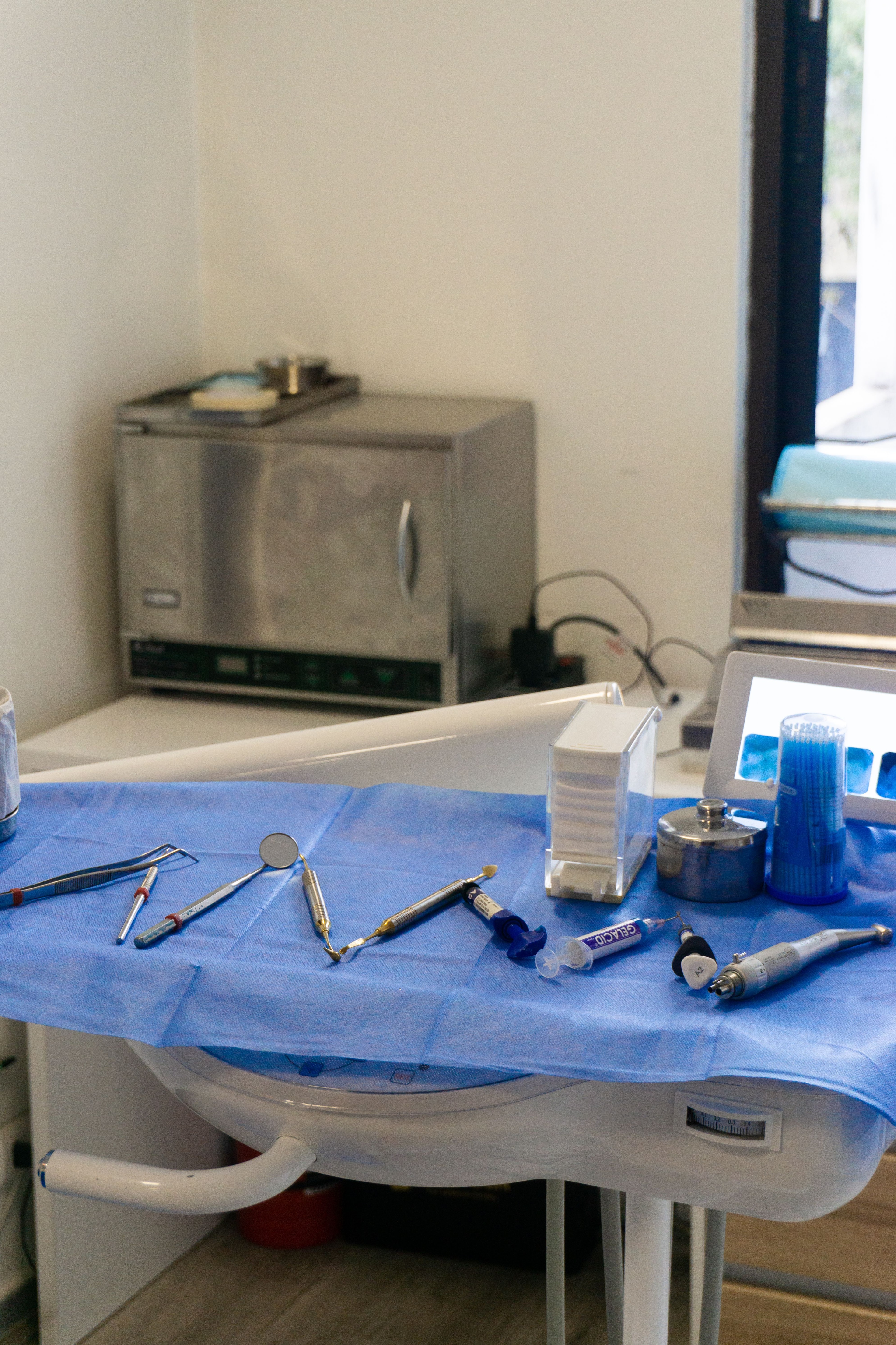 Dentalinstrumenter ligger på et afdækket klinikbord.