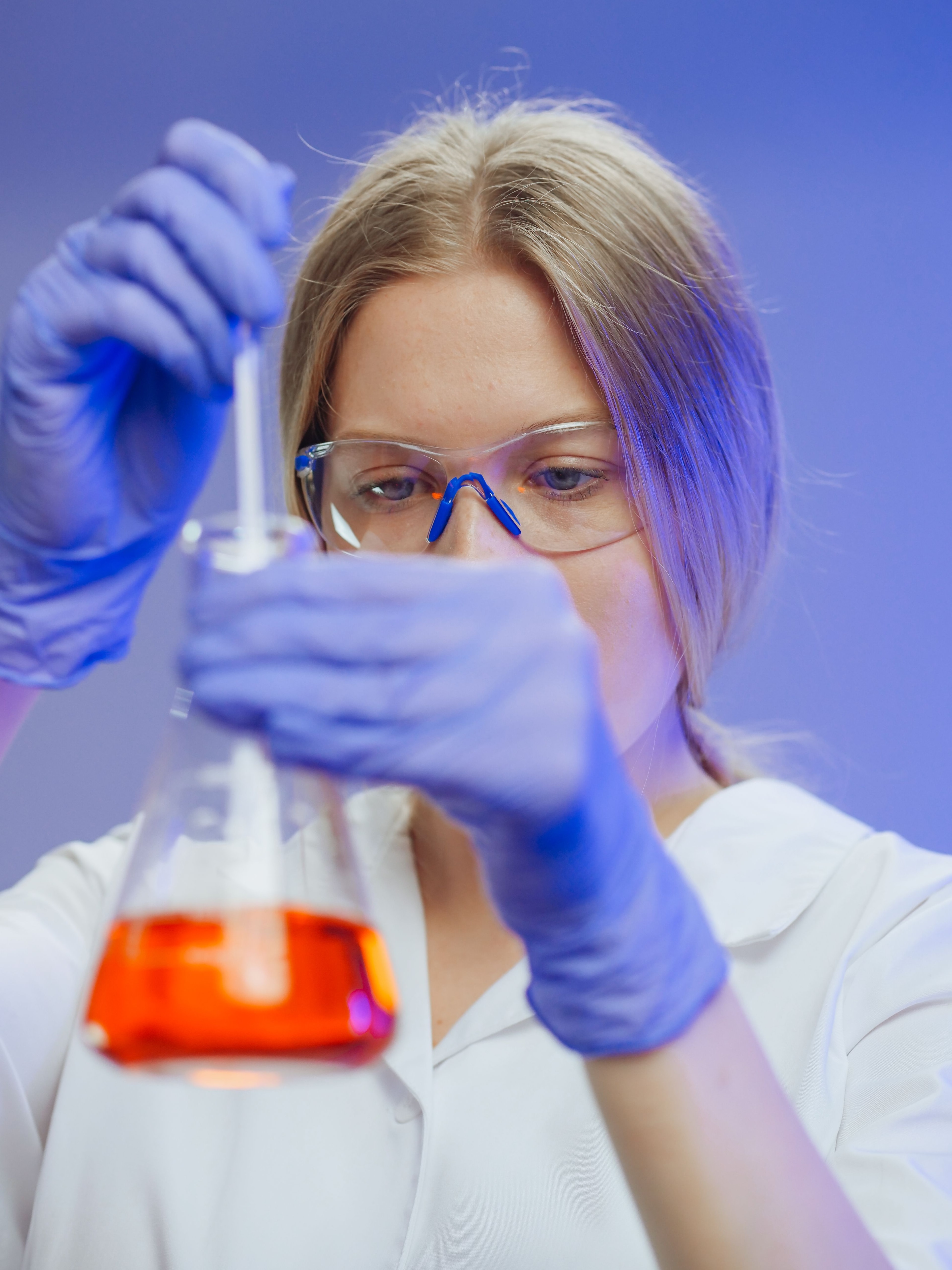 Laboratoriemedarbejder undersøger væske i en kolbe.