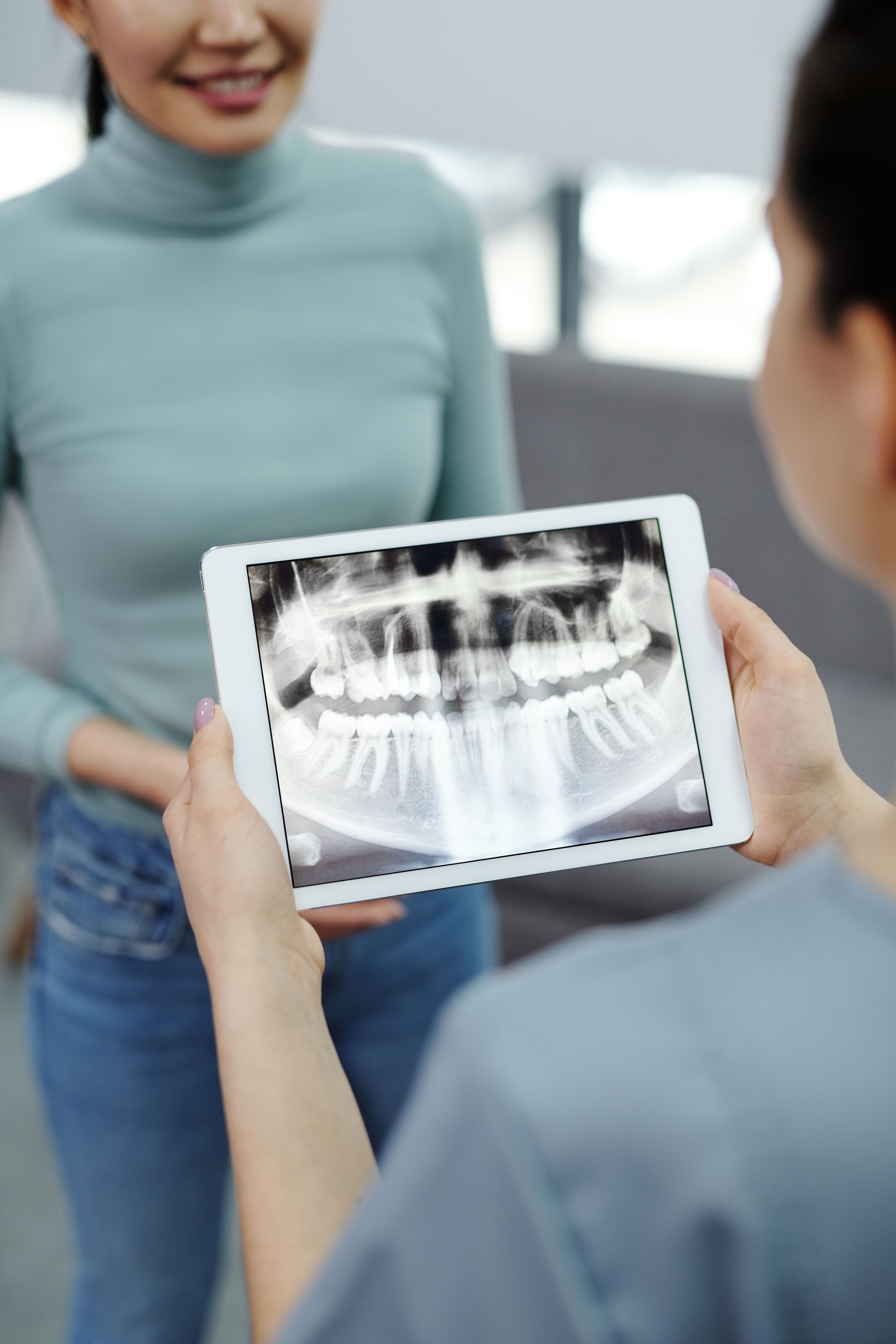 Behandler viser et panoramarøntgenbillede på en tablet til en patient.