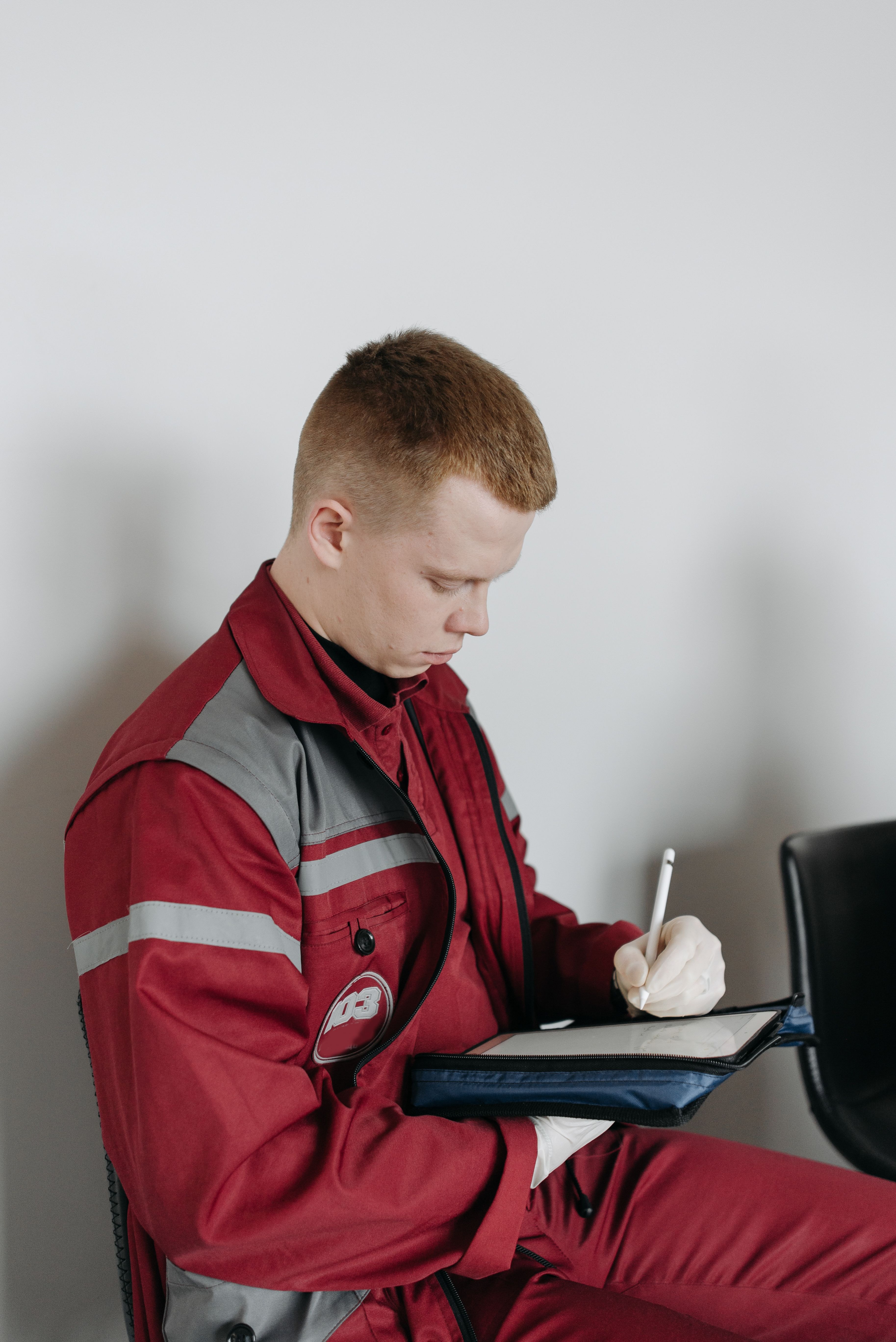 Redder noterer på en tablet i rødt arbejdstøj.