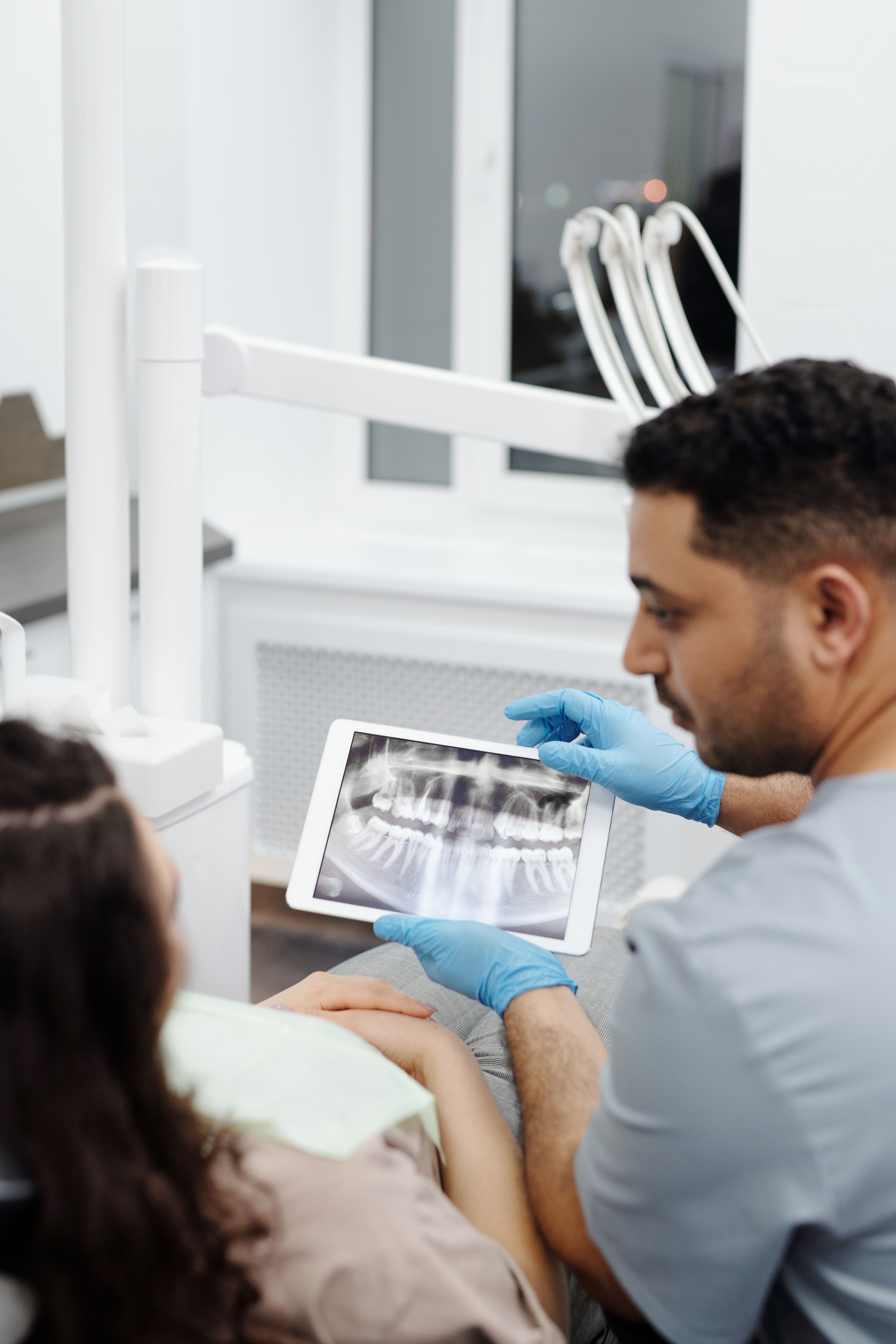 Tandlæge viser et røntgenbillede på en tablet til en patient.