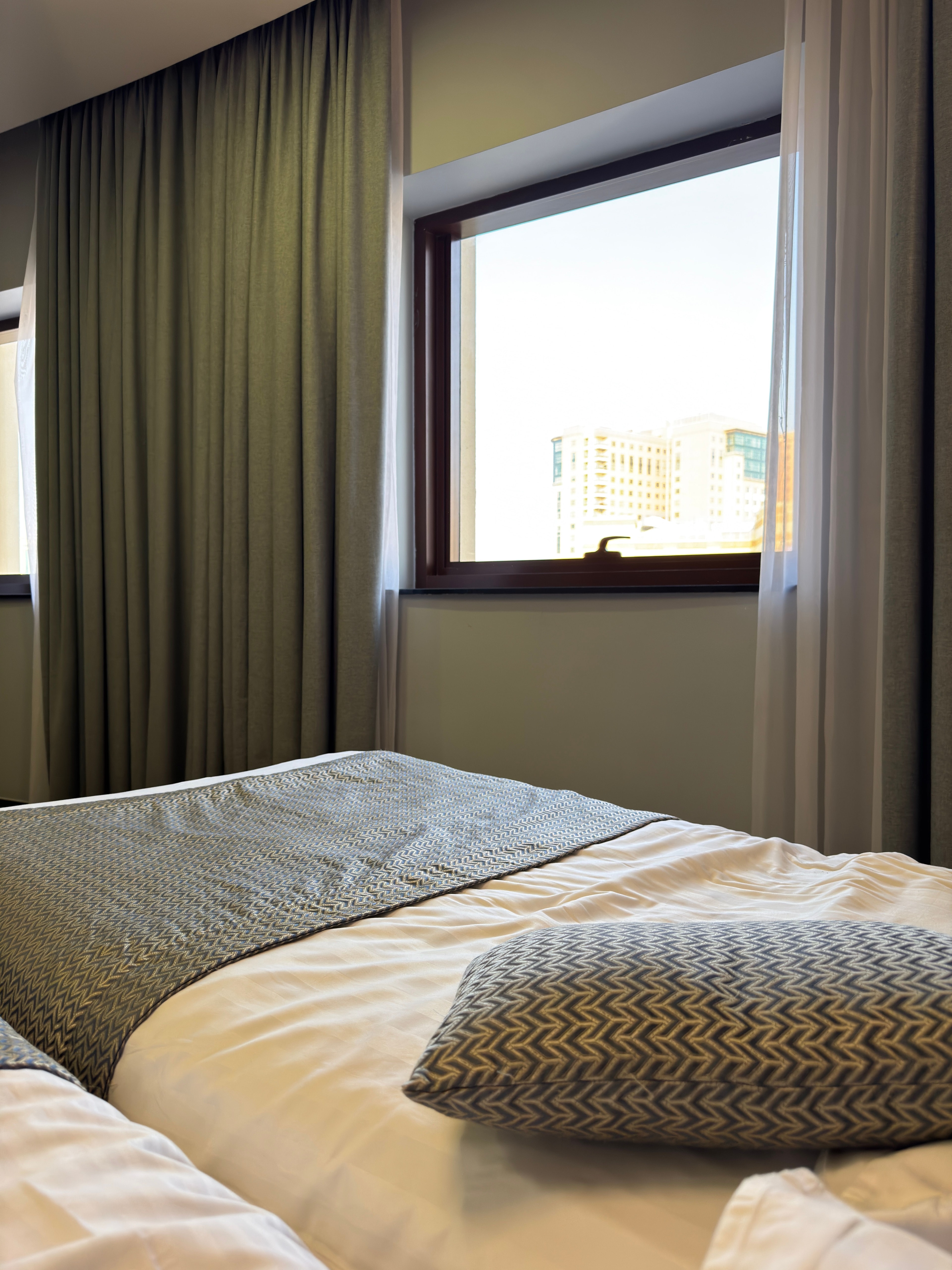 Hotelværelse med seng og udsigt gennem vinduet.