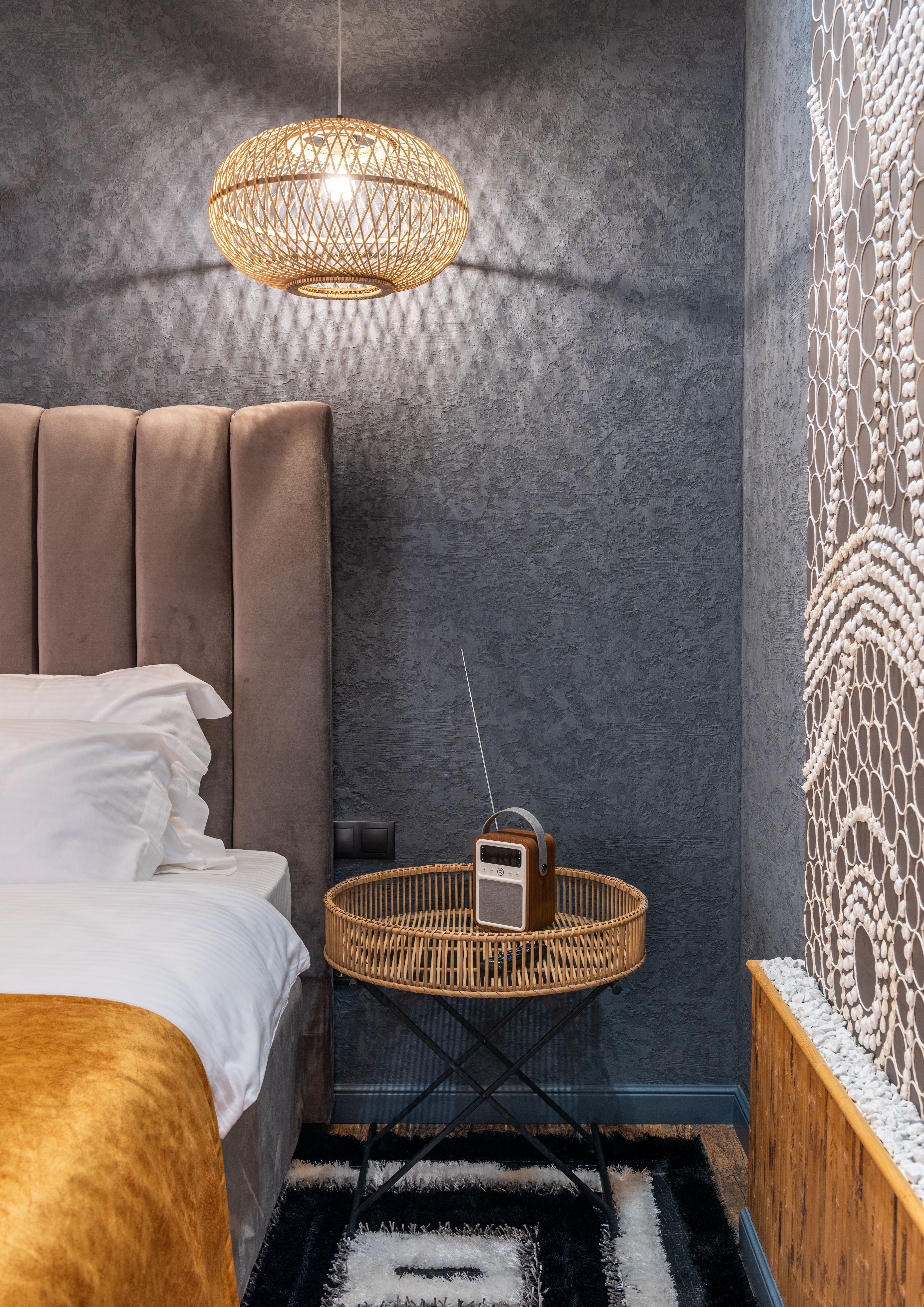 Hotelværelse med seng, natbord og varm belysning.