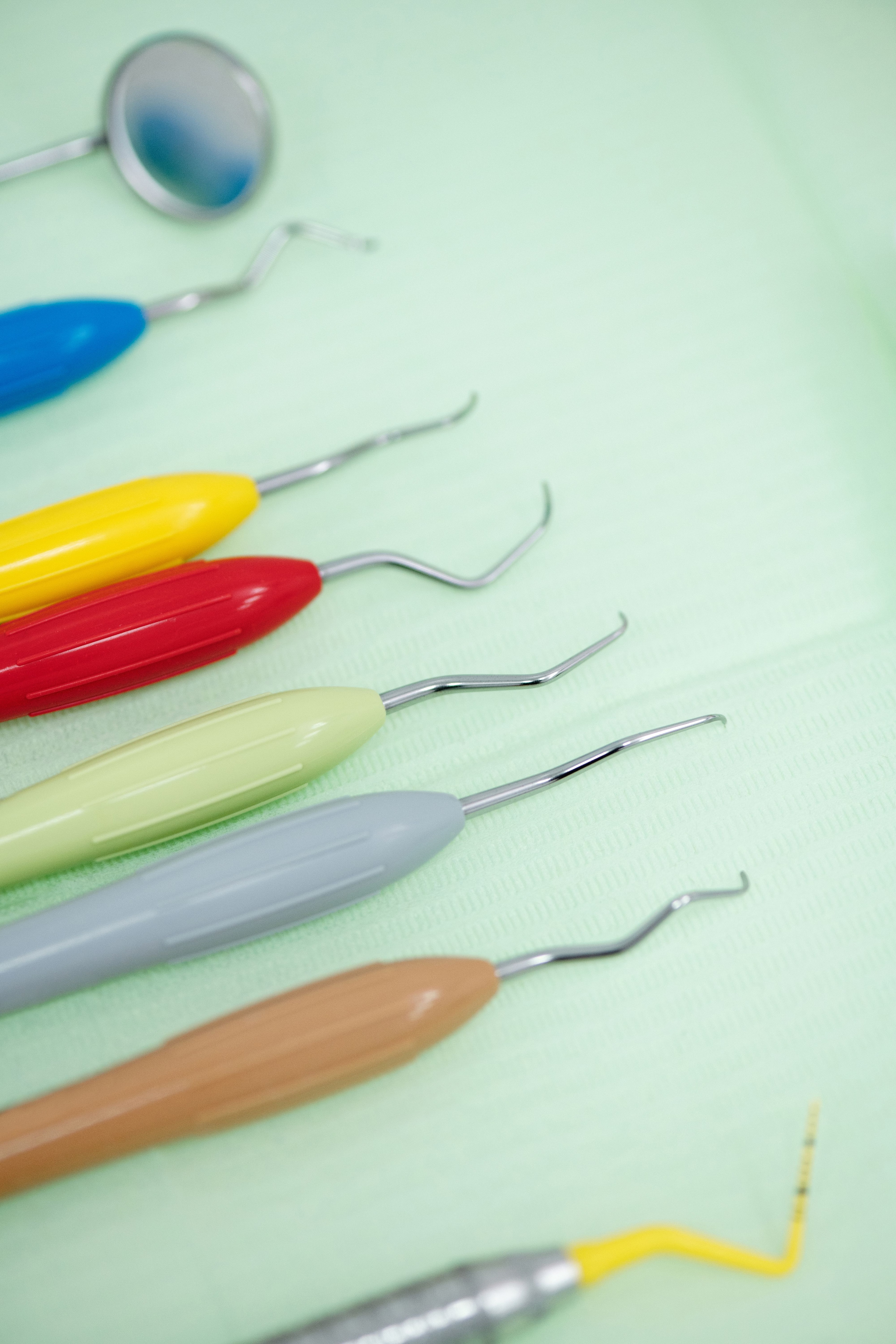 Farvede dentalinstrumenter ligger på en klinikbakke.