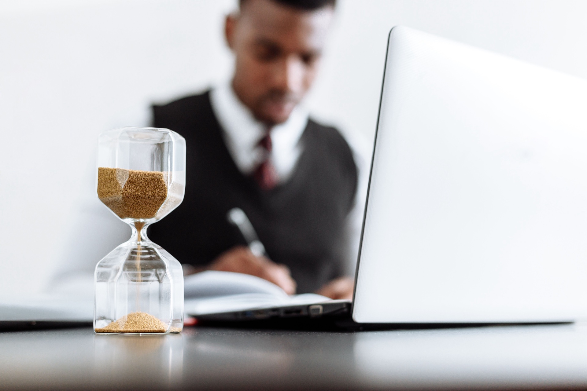 Timeglas står foran en person, der arbejder ved en bærbar computer.