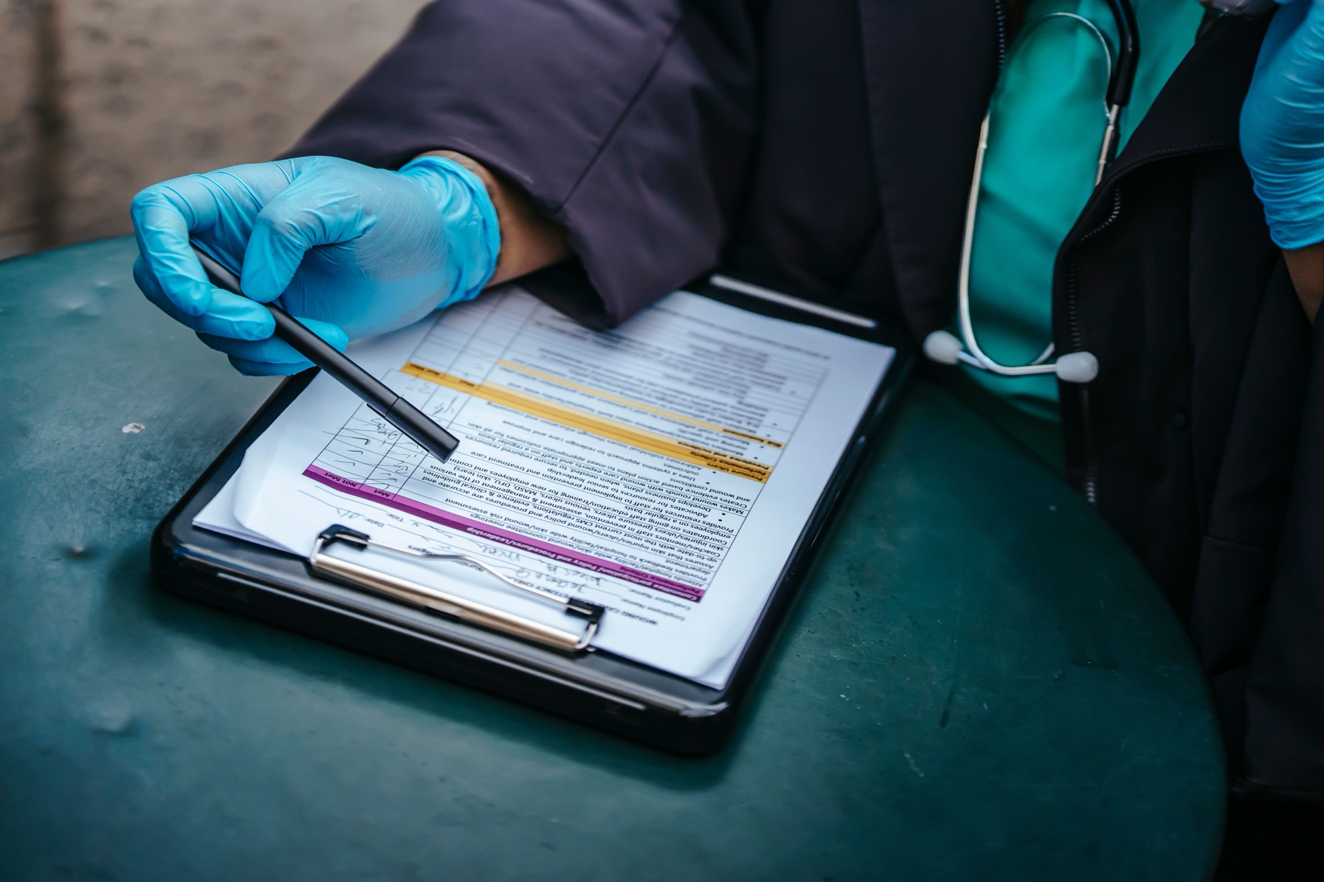 Sundhedsfaglig medarbejder udfylder et skema på en clipboard.